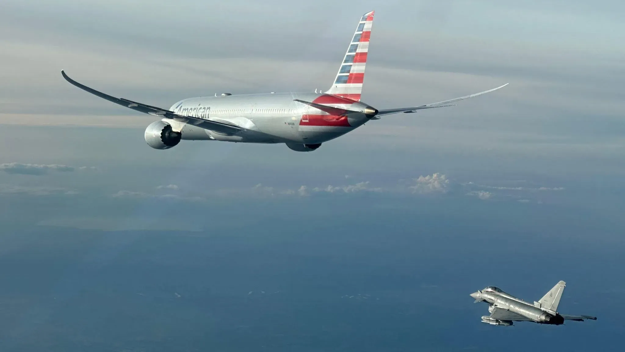 طائرة تابعة للخطوط الجوية الأمريكية تحلق بجانب طائرة مقاتلة فوق السحاب، بعد تحويل مسارها بسبب مخاوف أمنية.