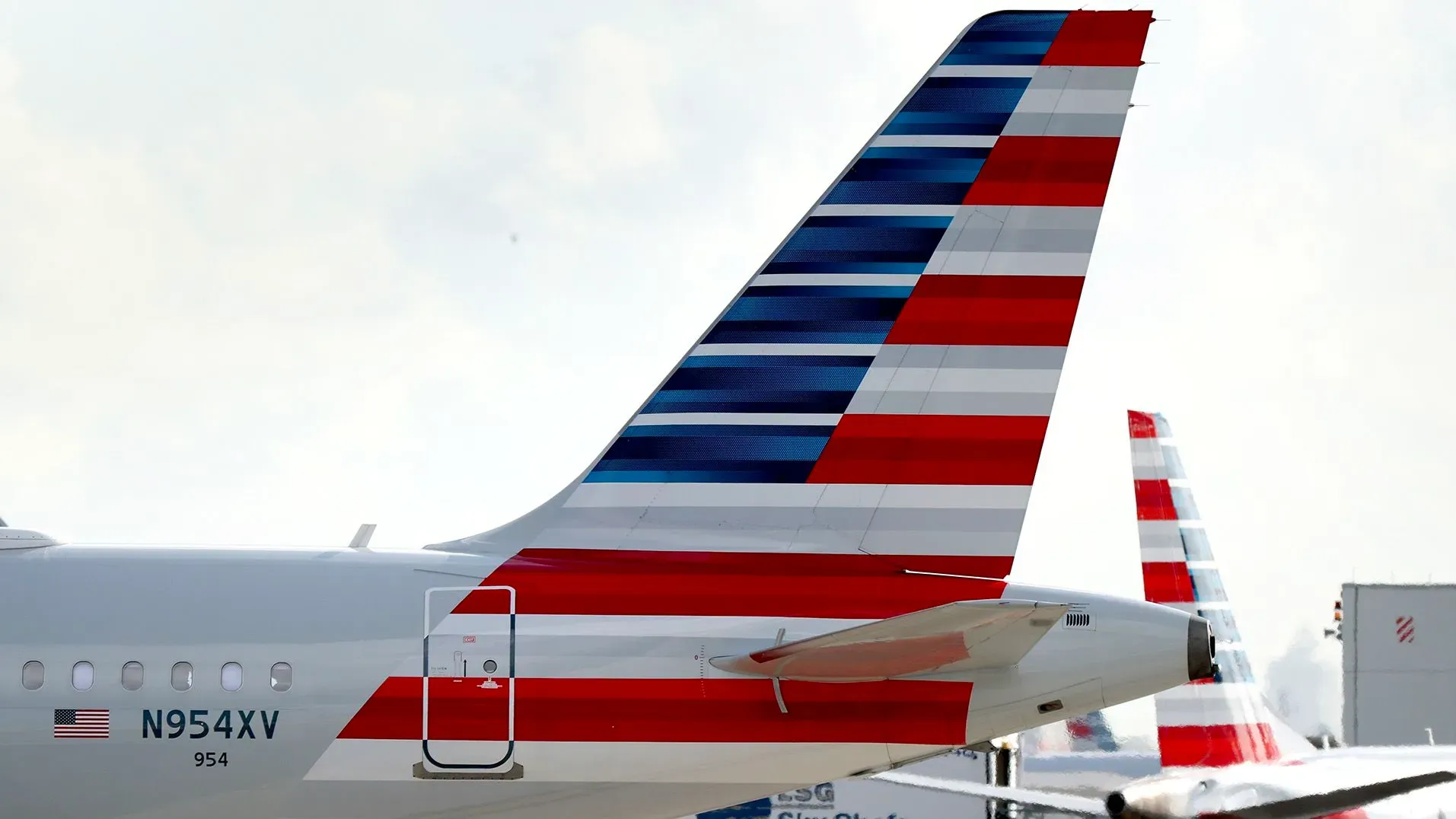 ذيل طائرة تابعة للخطوط الجوية الأمريكية يظهر تصميم الألوان الأحمر والأزرق، مع تفاصيل عن قرب من المطار، استعدادًا لتوفير خدمة الواي فاي المجانية.