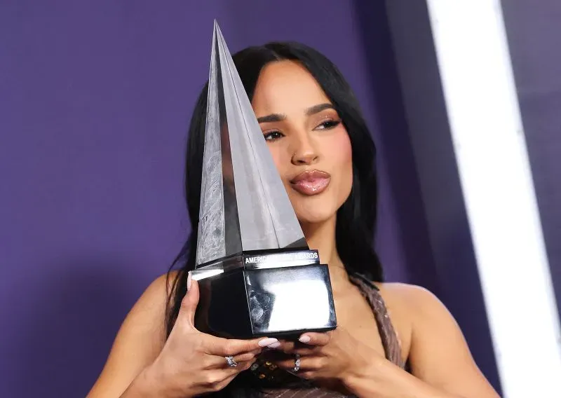 بيلي إيليش تحمل جائزة في حفل توزيع جوائز الموسيقى الأمريكية، تعبيرات الفرح واضحة على وجهها.