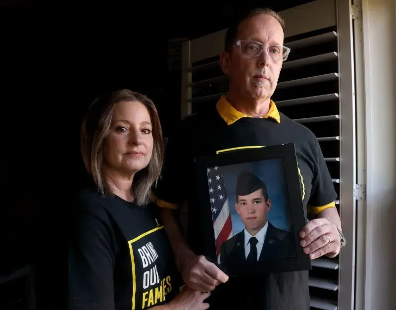 زوجان يحملان صورة لجوزيف سانت كلير، قدامى المحاربين المحتجزين في فنزويلا، يرتديان قمصانًا تحمل عبارة "أعيدوا عائلاتنا".