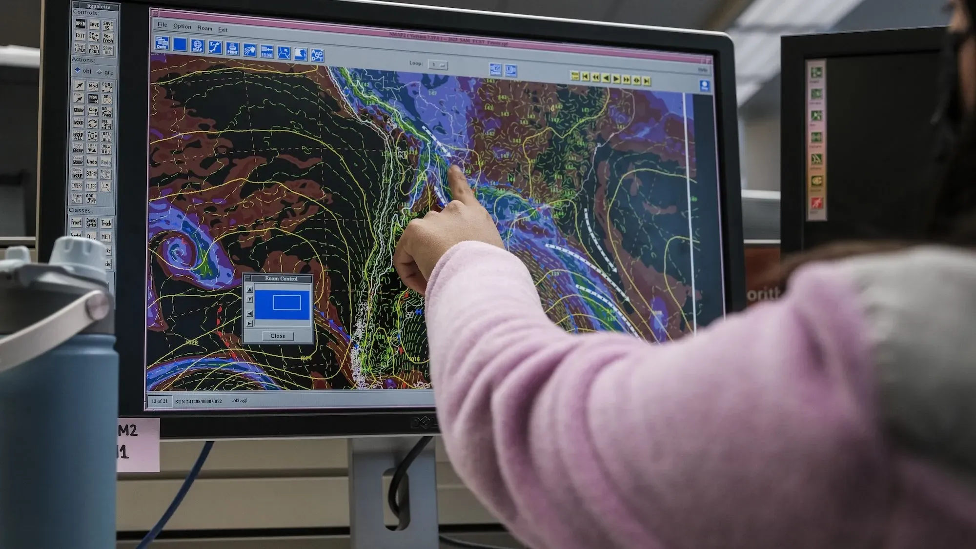 شخص يشير إلى شاشة حاسوب تعرض بيانات الأرصاد الجوية والخرائط، في سياق تأثير الإقالات داخل الإدارة الوطنية للمحيطات والغلاف الجوي.