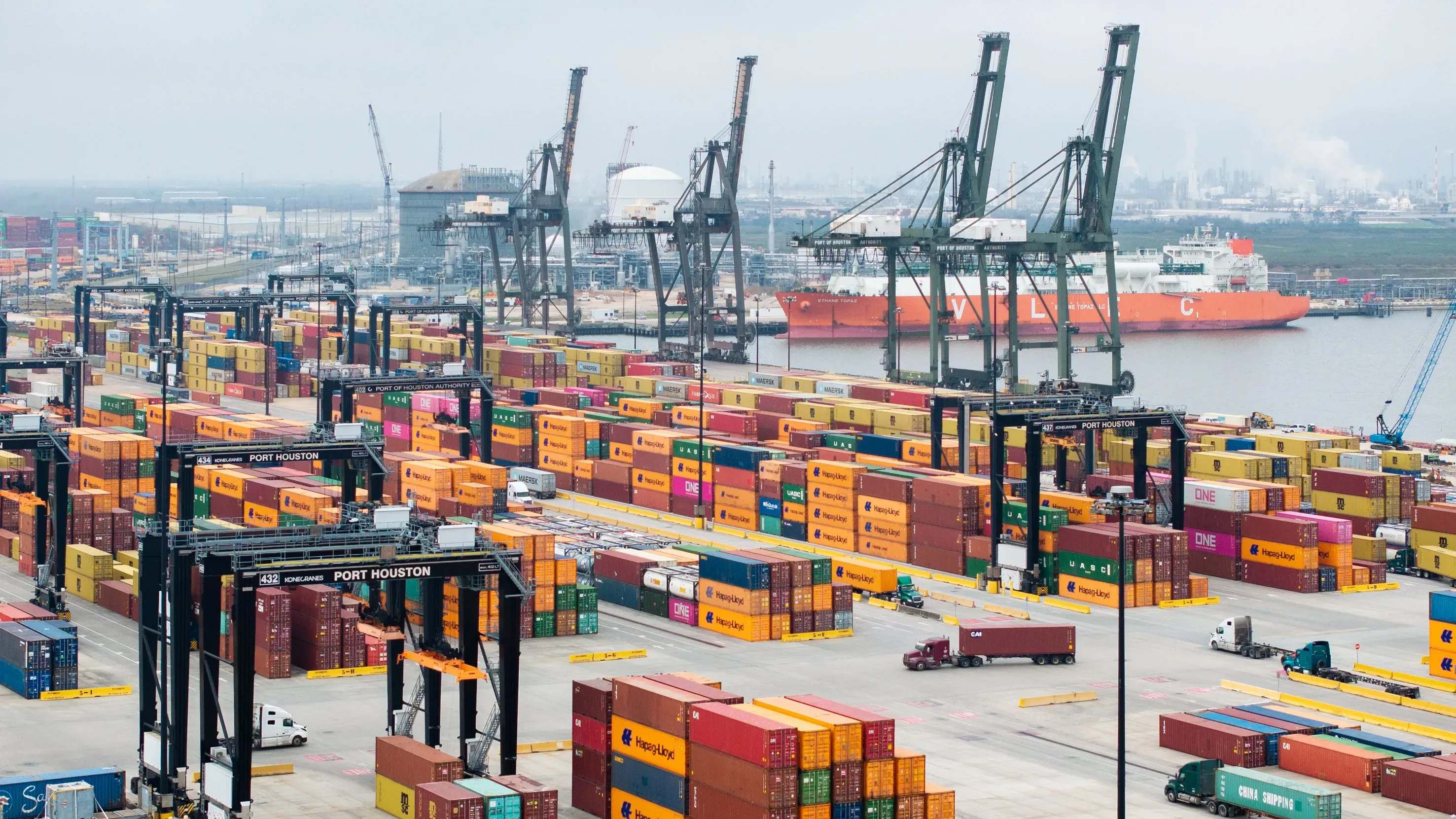 مستودع حاويات في ميناء هيوستن، يظهر حاويات ملونة وشاحنات، مما يعكس تأثير التعريفات الجمركية على التجارة الأمريكية.