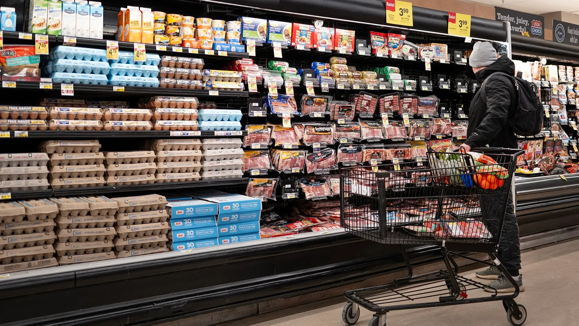 متسوق يقف أمام رفوف السوبرماركت، يتفحص البيض واللحوم، وسط مخاوف من ارتفاع التضخم وتأثيره على الأسعار.