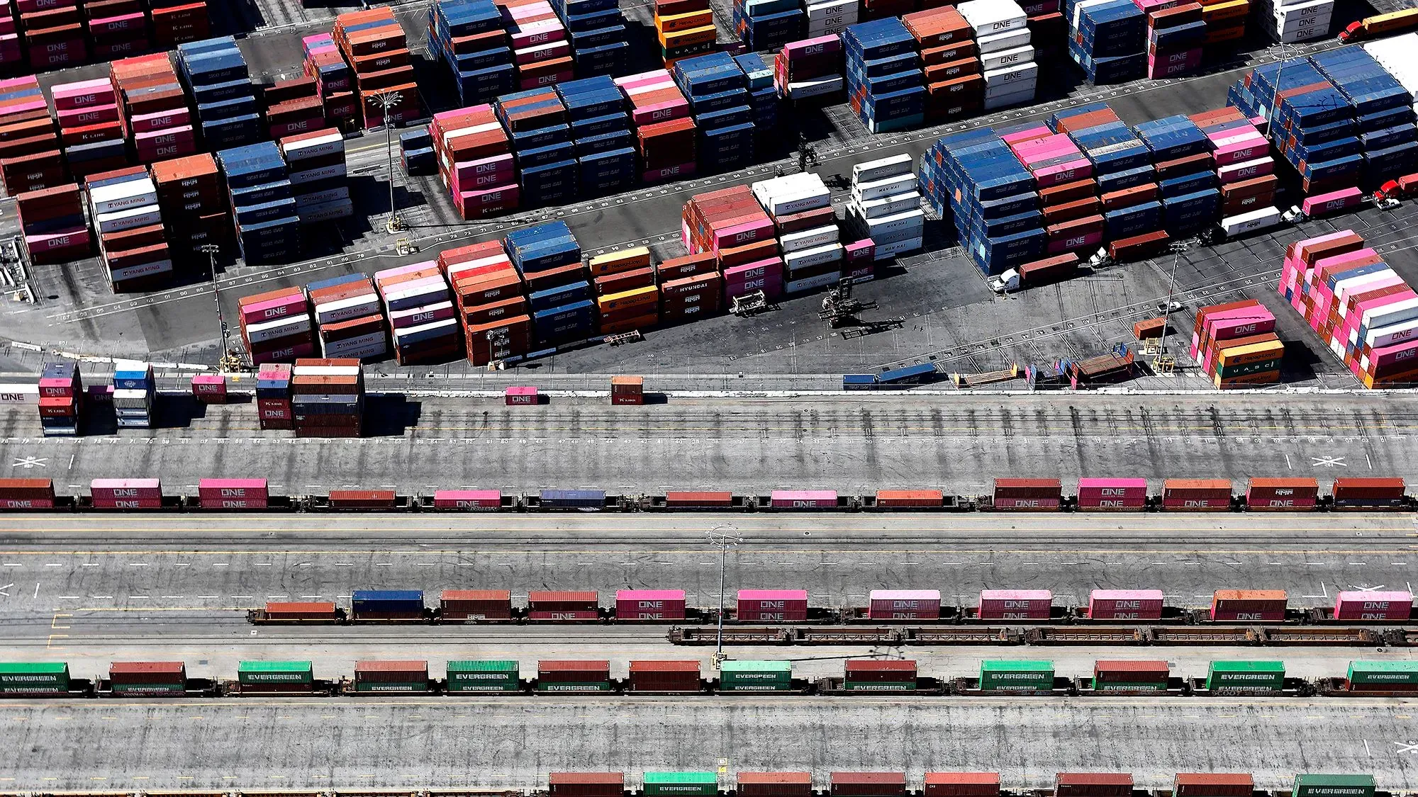 صورة تظهر حاويات شحن ملونة مرتبة في ميناء، تعكس تأثير التعريفات الجمركية على الاقتصاد الأمريكي وزيادة الواردات.