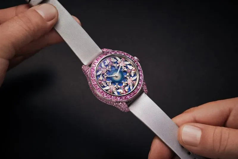 ساعة أنثوية فاخرة من شوبارد، مزينة بأحجار ملونة، تتضمن تفاصيل دقيقة من الألماس والمواد الطبيعية، تعكس تراث العلامة.