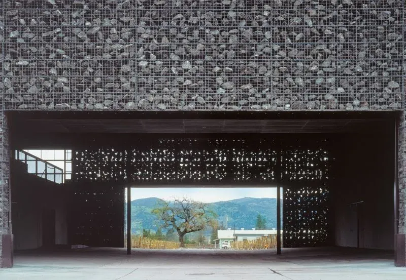 تصميم معماري مبتكر يجسد استخدام الحمم البركانية في البناء، مع جدران مصنوعة من الصخور البركانية، خلفية طبيعية جبلية.