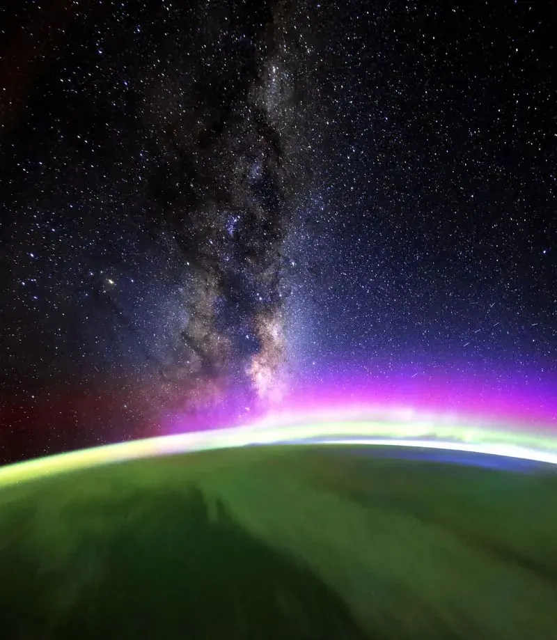 منظر فضائي مذهل يظهر درب التبانة مع أضواء الشفق القطبي فوق الأرض، مما يعكس جمال الكون من محطة الفضاء الدولية.