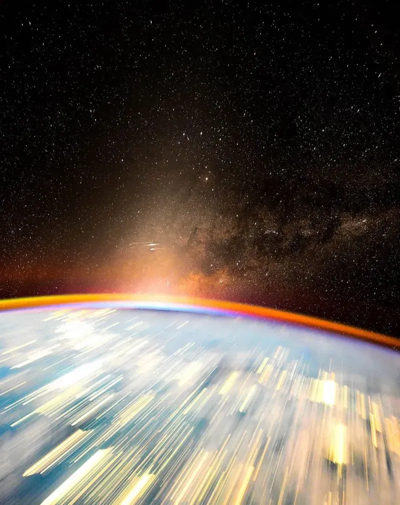 صورة تظهر الأفق الأرضي من الفضاء مع تأثير الحركة، حيث يضيء ضوء النجوم والغيوم في الخلفية، تعكس جمال الكون من منظور رائد الفضاء دون بيتيت.