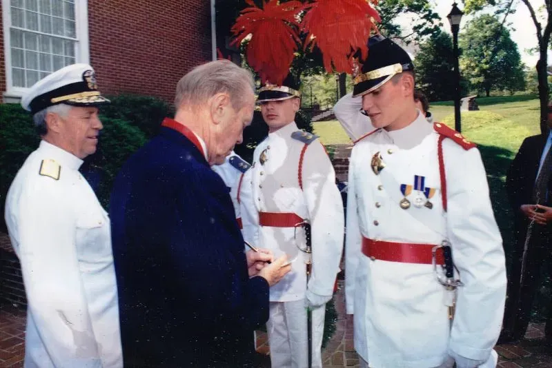 صورة لرجل مسن يتحدث مع ضباط في زي رسمي، بينما يظهر خلفهم ضباط آخرون. تعكس اللحظة أهمية التاريخ الأمريكي.