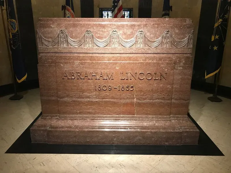 قبر الرئيس الأمريكي أبراهام لينكولن، مكتوب عليه اسمه وتواريخ حياته، محاط بأعلام الولايات.