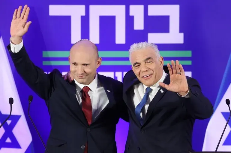 يظهر في الصورة Naftali Bennett وYair Lapid، وهما يعلنان استئناف تحالفهما السياسي في Herzliya، وسط خلفية تحمل شعار حزب "معاً".