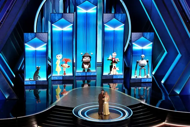 غولدي هاون وأندرو غارفيلد على المسرح خلال حفل توزيع جوائز الأوسكار، مع خلفية ملونة تعرض شخصيات كرتونية.