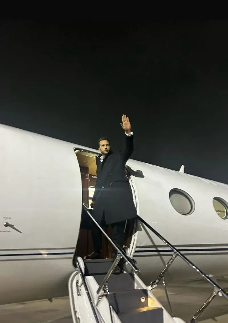 أندرو تيت يلوح بيده أثناء مغادرته على متن طائرة خاصة من رومانيا إلى فلوريدا، بعد رفع القيود المفروضة عليه.