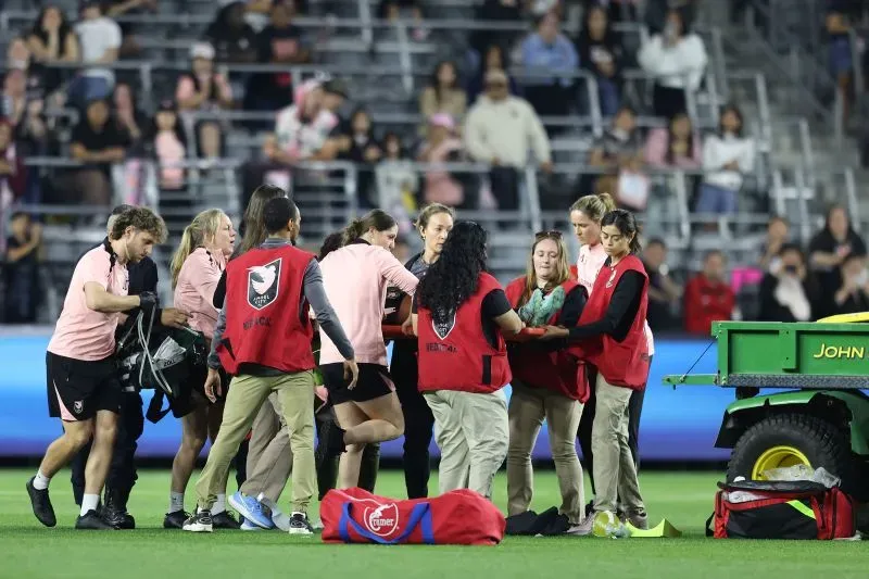تجمع الطاقم الطبي حول سافي كينغ، لاعبة أنجل سيتي، بعد سقوطها خلال مباراة دوري NWSL، مع وجود سيارة إسعاف في الخلفية.
