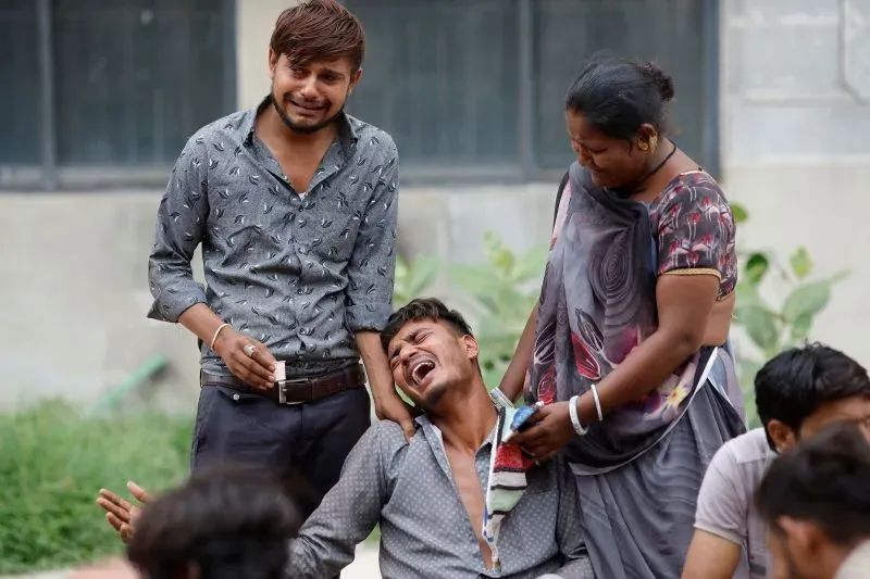 عائلة مفجوعة تجلس في مستشفى أحمد آباد، تعبر عن حزنها بعد حادث تحطم الطائرة، حيث فقدت أحد أحبائها.