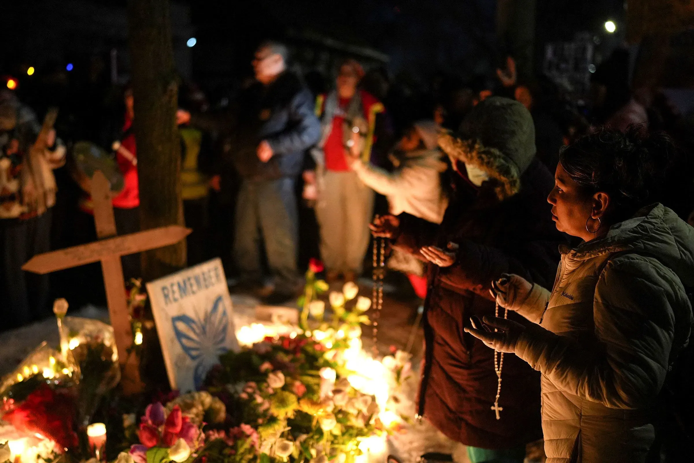 تجمع حشود من الناس في مينيابوليس لإحياء ذكرى رينيه نيكول جود، حيث يحملون الشموع والصلبان وسط أجواء حزينة.