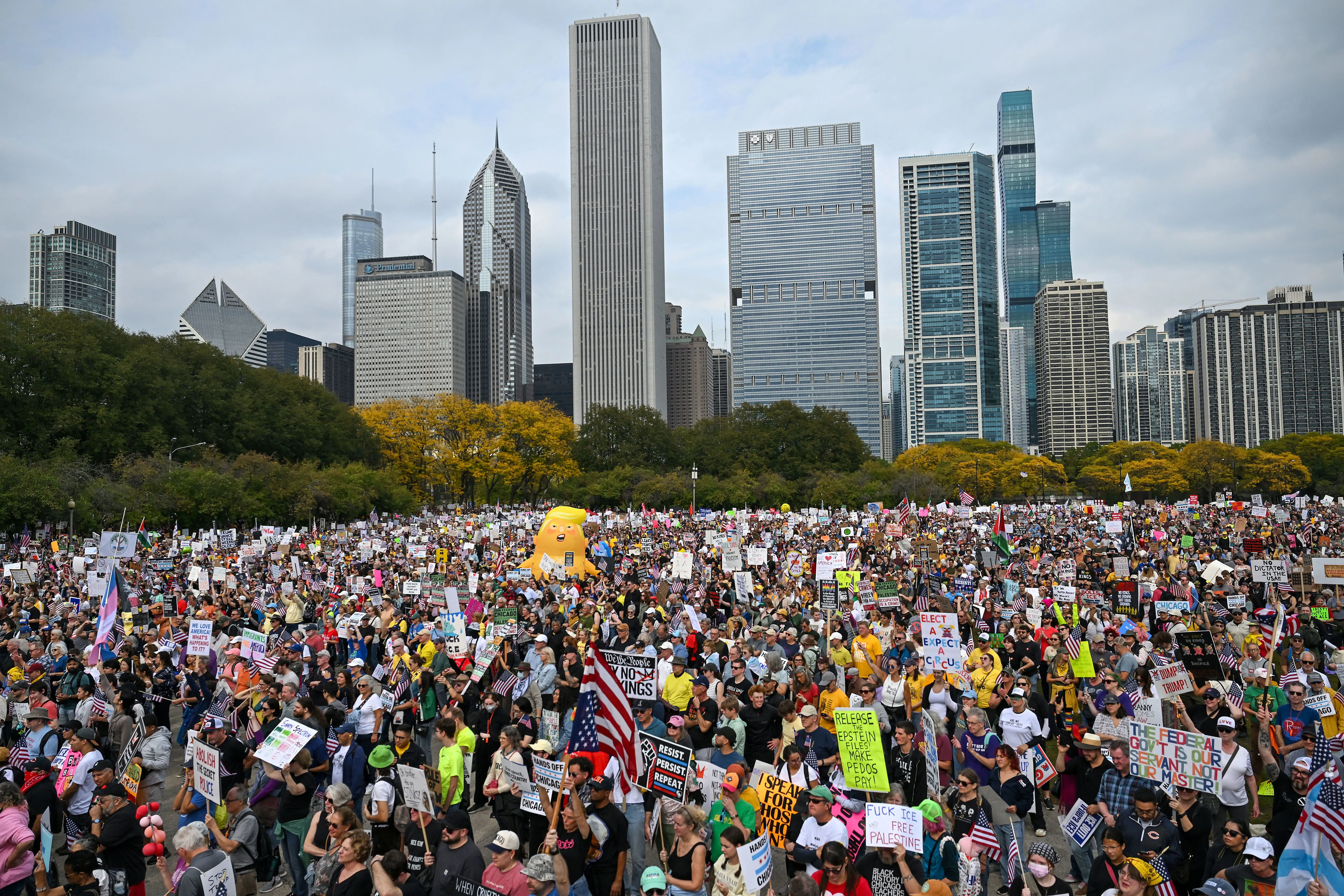 مظاهرة حاشدة في شيكاغو تضم آلاف المشاركين يحملون لافتات تعبر عن آراء سياسية متنوعة، مع خلفية ناطحات السحاب.