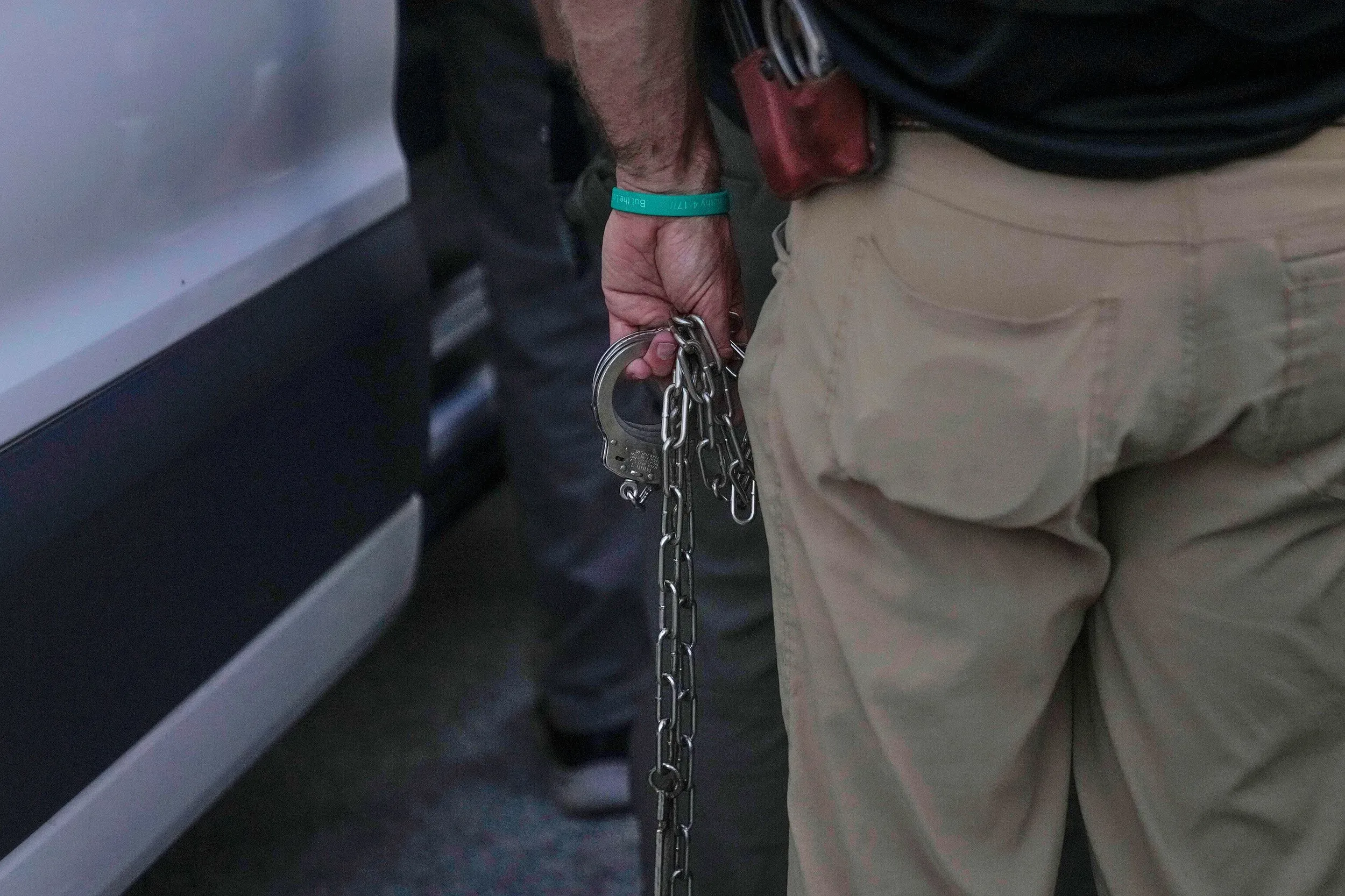 رجل يحمل الأصفاد المعدنية، مما يعكس إجراءات الاعتقال للمهاجرين في شيكاغو، وسط تطورات قانونية بشأن الإفراج عنهم.
