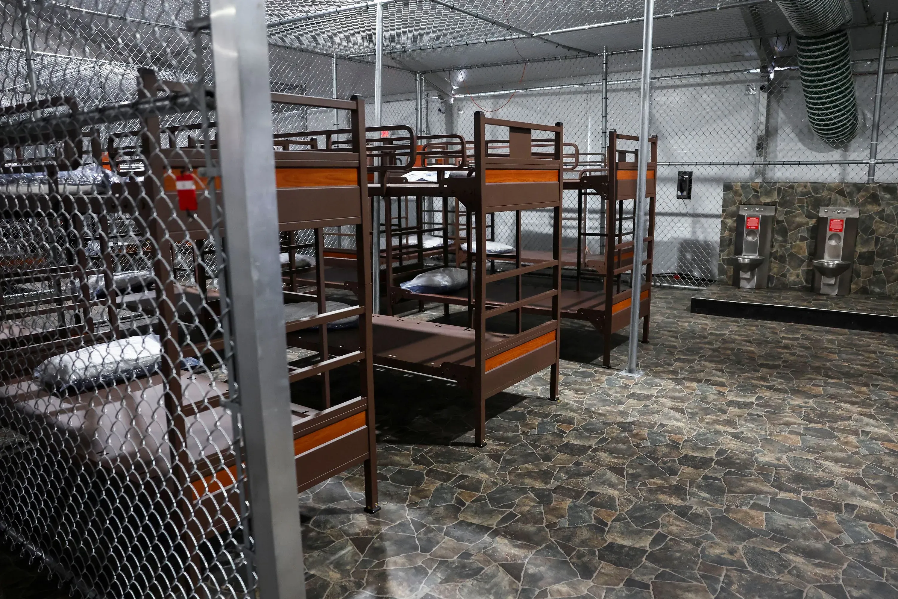 منشأة احتجاز المهاجرين في إيفرجليدز، مع أسرة بطابقين محاطة بسياج معدني، تعكس الوضع الحالي للقضية القانونية حول إغلاقها.