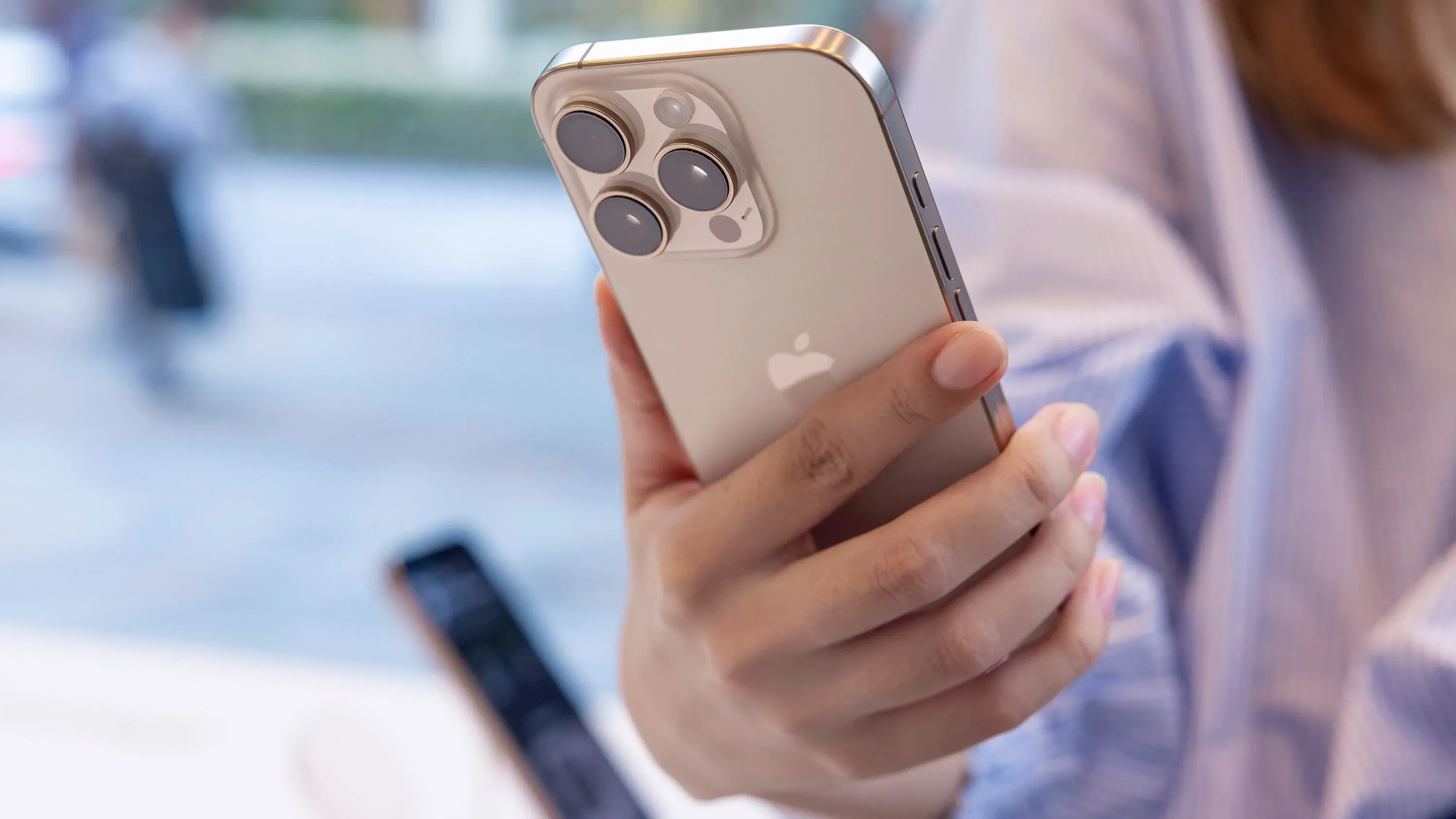 هاتف آيفون من شركة آبل في يد مستخدم، مع التركيز على الكاميرا الخلفية، في سياق الحديث عن خلل في نظام الإملاء الصوتي.