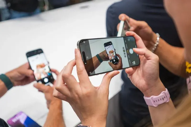 أشخاص يستخدمون هواتفهم الذكية لالتقاط صور خلال حدث تقني، مما يعكس اهتمامهم بالتكنولوجيا الحديثة والابتكارات.