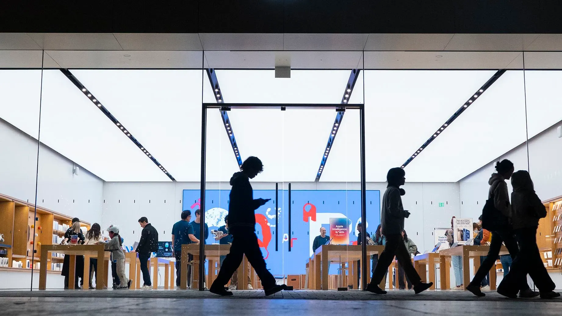 واجهة متجر Apple مع زبائن يتصفحون الأجهزة، مما يعكس الاهتمام المتزايد بالإصدارات الجديدة مثل iPhone النحيف المتوقع.