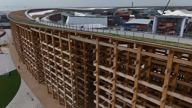 هيكل خشبي ضخم في إكسبو 2025 بأوساكا، يمثل رمز الوحدة، مصنوع من الأخشاب اليابانية، ويحيط بمساحة المعرض.