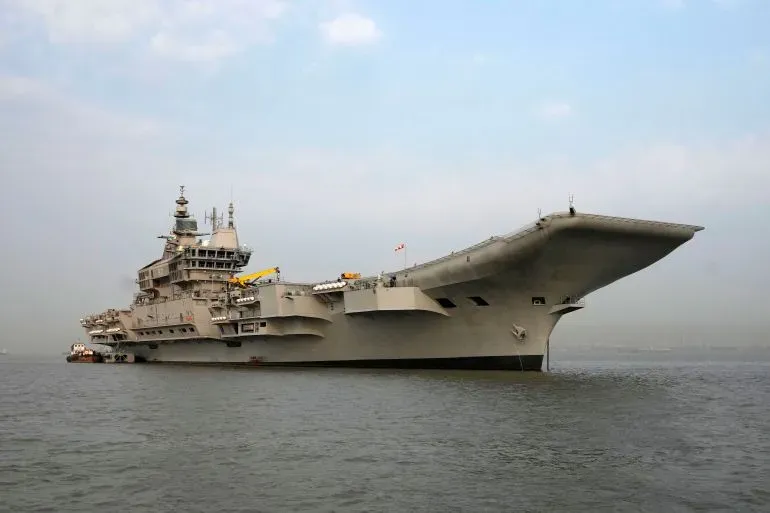 حاملة الطائرات الهندية "آي إن إس فيكرانت" راسية في البحر، تظهر في الخلفية أجواء هادئة، تعكس التوترات العسكرية بين الهند وباكستان.