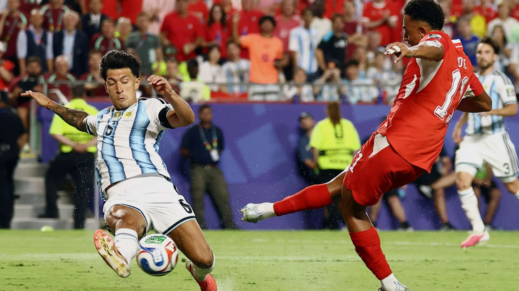 لاعب أرجنتيني يرتدي قميص رقم 6 ينفذ تدخلًا دفاعيًا ضد لاعب سويسري في مباراة حماسية ضمن تصفيات كأس العالم.