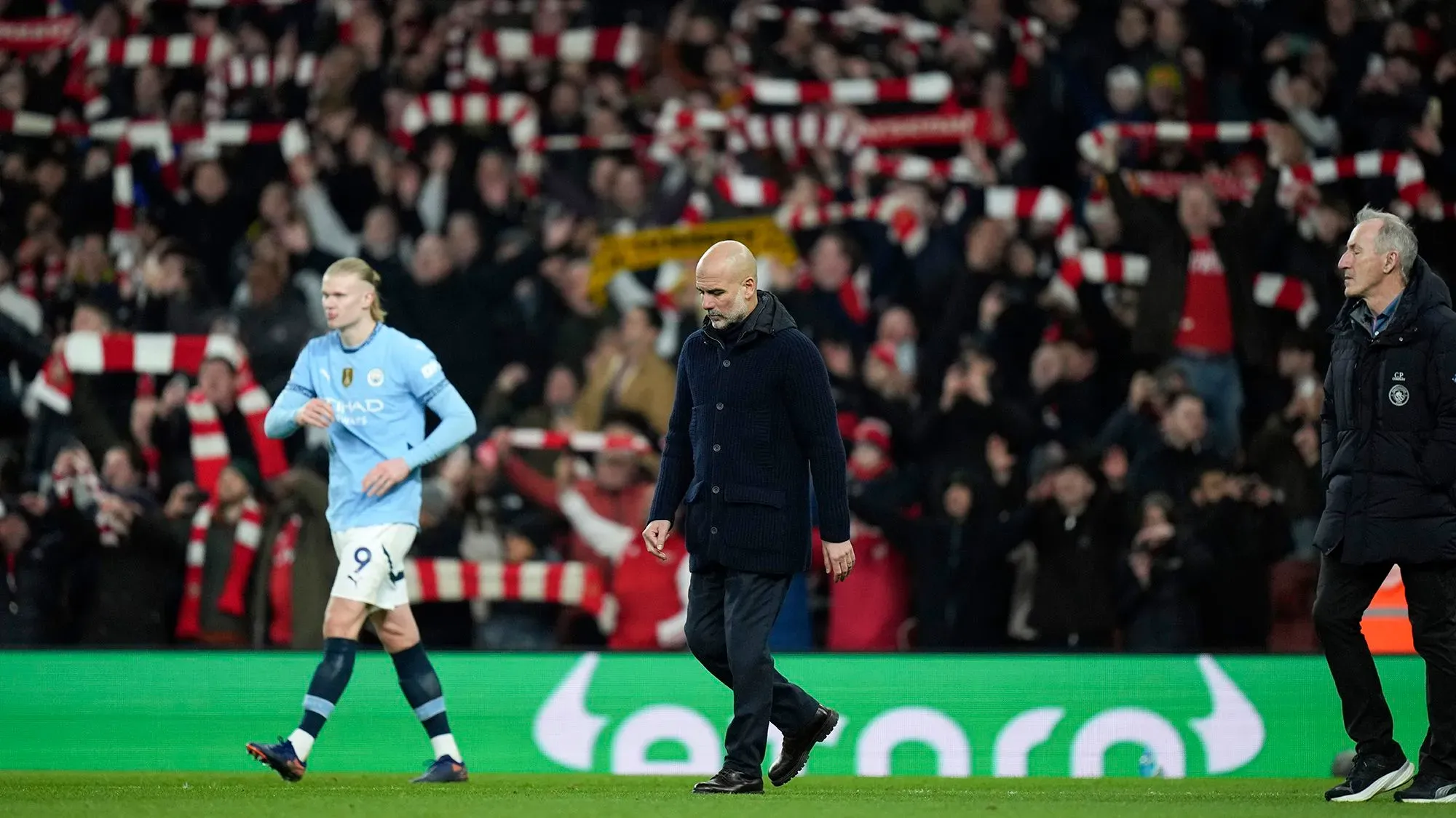 هزيمة مانشستر سيتي 5-1 أمام أرسنال، مع هالاند في المقدمة وجوارديولا يظهر علامات الإحباط، وسط أجواء حماسية من الجماهير.