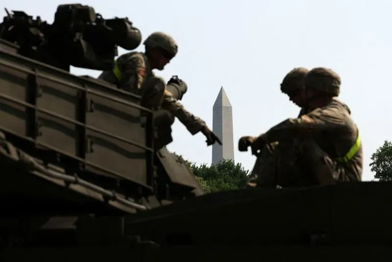 جنود أمريكيون يجلسون على دبابة في واشنطن، مع نصب واشنطن في الخلفية، خلال الاستعدادات لاستعراض عسكري بمناسبة عيد ميلاد الجيش.