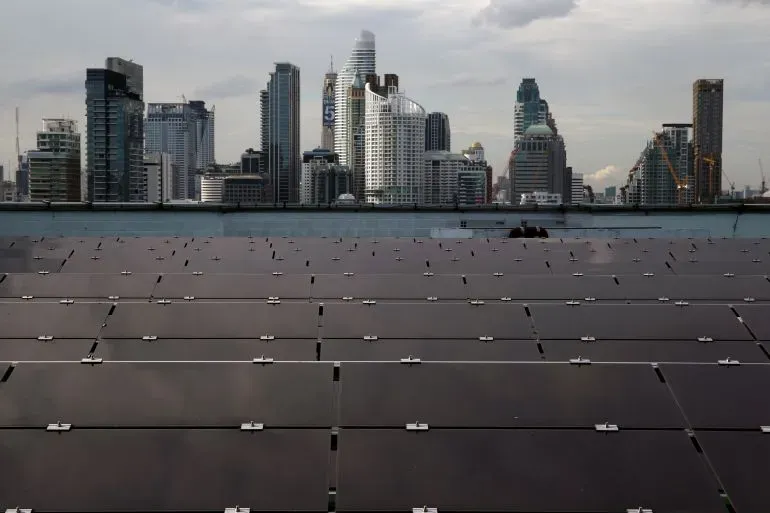 ألواح شمسية على سطح مبنى في بانكوك، مع skyline المدينة في الخلفية، تعكس تأثير الرسوم الجمركية الأمريكية على صناعة الطاقة الشمسية في تايلاند.