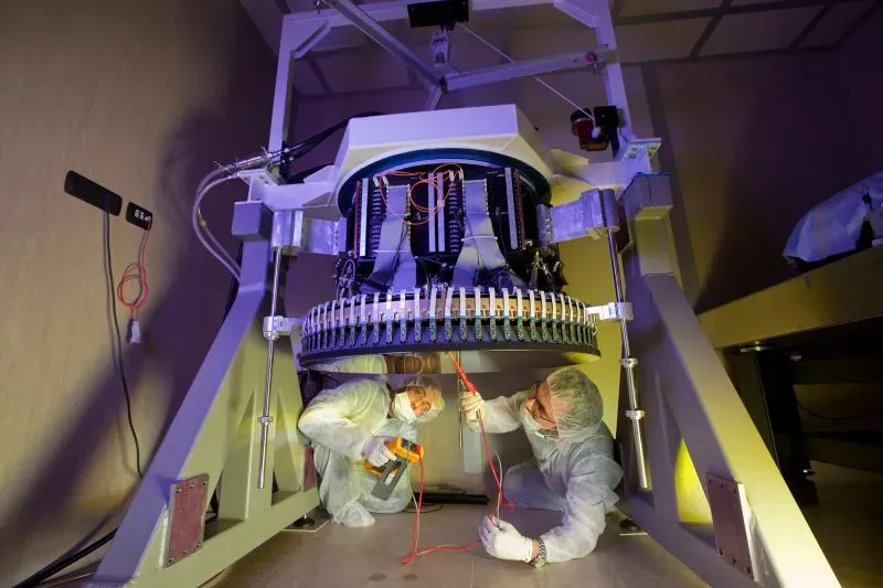 فريق من العلماء يقوم بتعديل معدات تلسكوب، مع التركيز على الأجزاء التقنية، في إطار البحث عن مجرات بقايا قديمة.