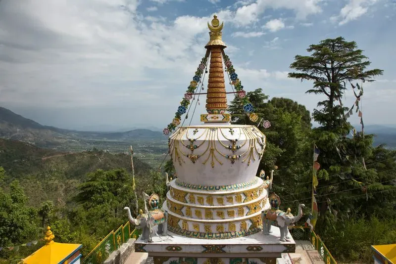 ستوبا مزينة بألوان زاهية، محاطة بأشجار خضراء وجبال، تمثل رمزًا ثقافيًا وروحيًا مهمًا للتبت في سياق نضالها ضد الحكم الصيني.