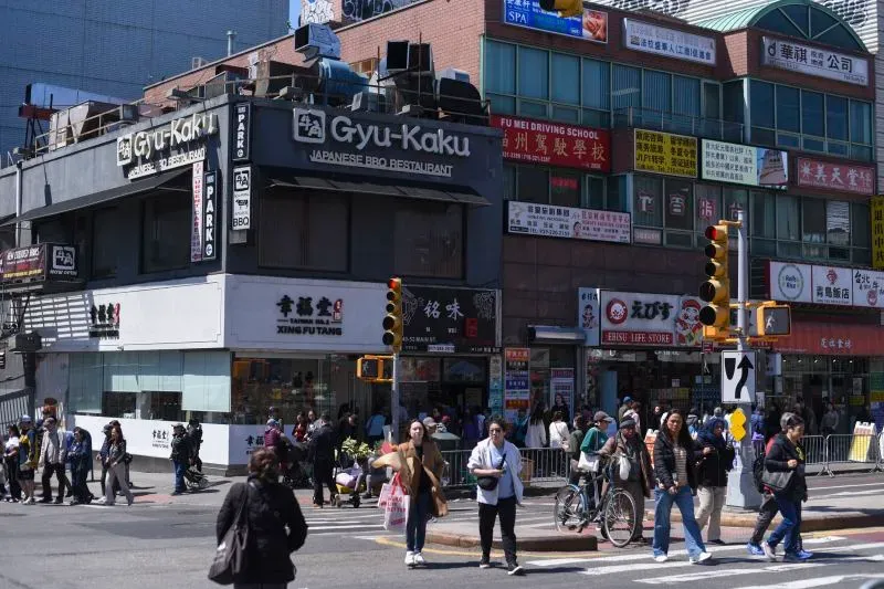 واجهة سوبر ماركت تشانغ جيانغ في فلاشينغ، كوينز، مع لافتات باللغة الصينية وازدحام للمتسوقين، تعكس تأثير الحرب التجارية على المجتمعات الآسيوية.