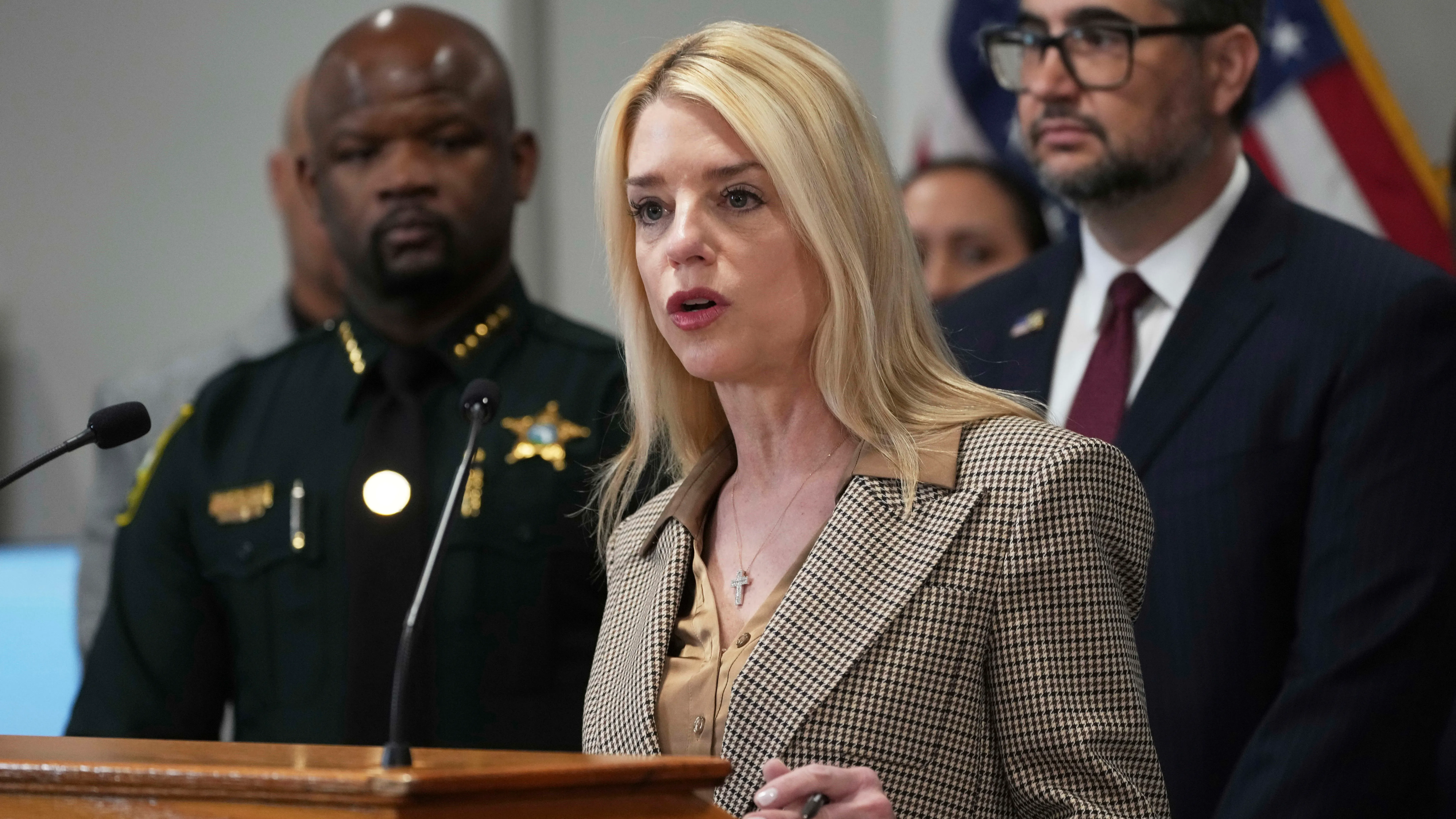 تظهر الصورة المدعي العام بام بوندي تتحدث خلال مؤتمر صحفي، مع ضباط خلفها، حول سياسة وزارة العدل الجديدة المتعلقة بالتسريبات الإعلامية.