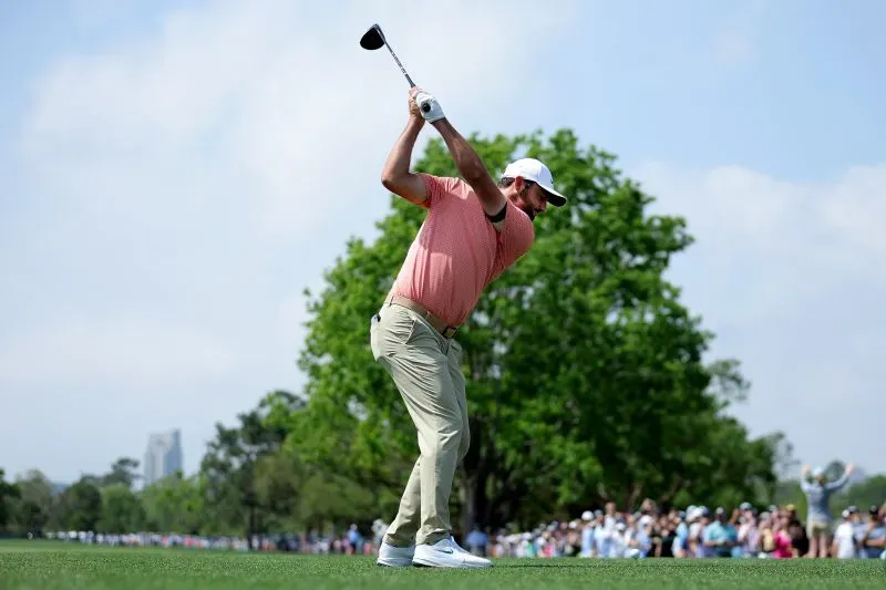 مين وو لي يضرب الكرة في بطولة هيوستن المفتوحة، محاطًا بجمهور كبير، مع أشجار خضراء في الخلفية.