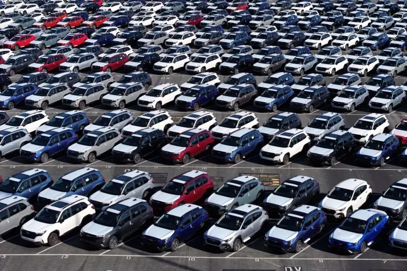 ازدحام كبير للسيارات الجديدة في موقف سيارات، يمثل تأثير التعريفات الجمركية على صناعة السيارات الأمريكية وارتفاع الأسعار المتوقع.