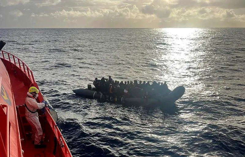 قارب مهاجرين مكتظ بـ 60 شخصًا، يبحر في مياه المحيط الأطلسي، مع قبطان سفينة الإنقاذ بالقرب من جزيرة لانزاروتي.