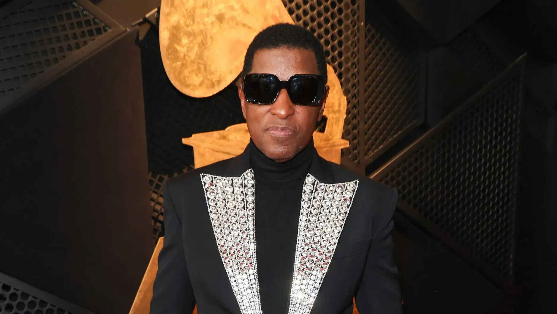 بيبي فيس، المغني والمنتج الحائز على 12 جائزة غرامي، يرتدي بدلة أنيقة مع تفاصيل لامعة، في حفل توزيع جوائز الغرامي.