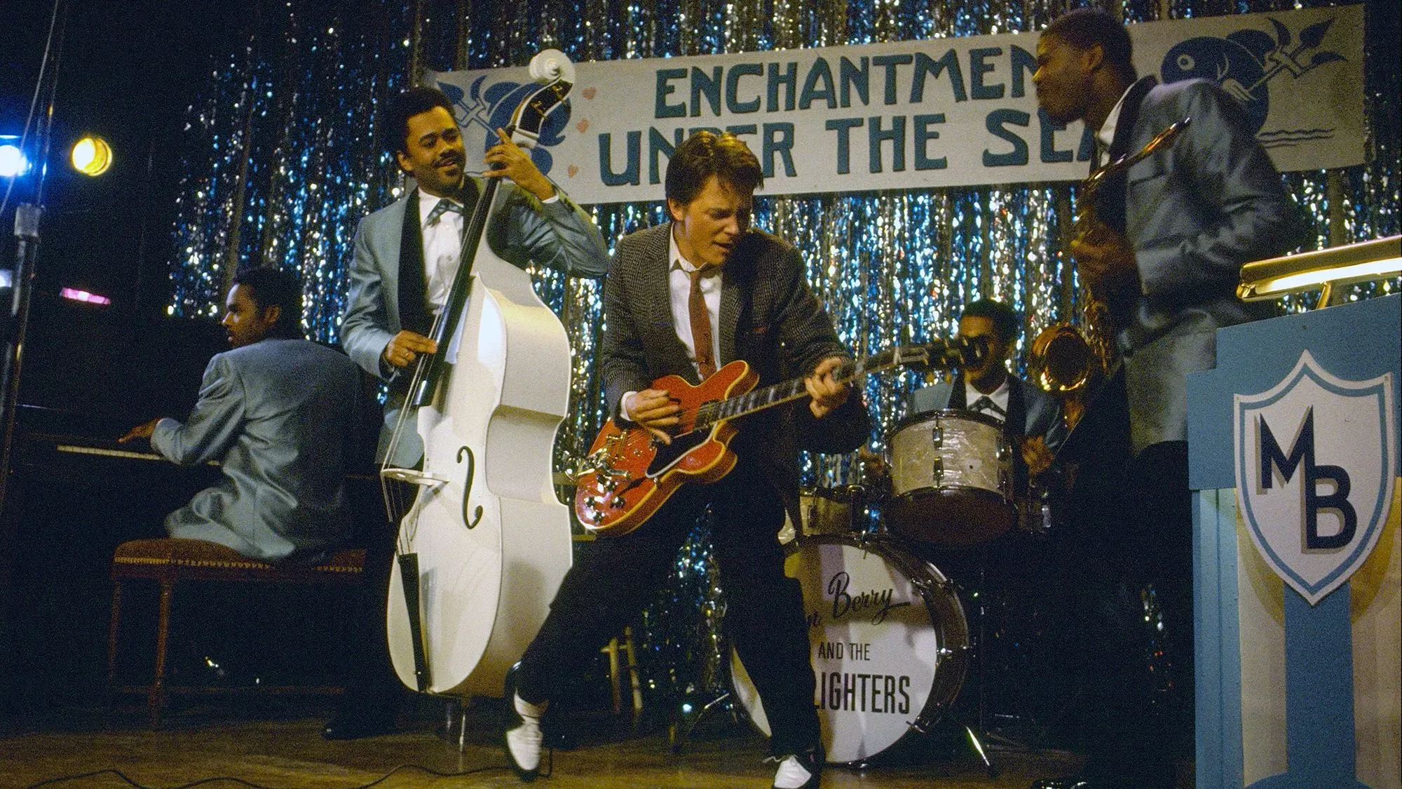 اجتماع الممثلين الأصليين لفيلم "العودة إلى المستقبل" خلال مشهد غنائي في حفلة مدرسية، مع التركيز على غيتار جيبسون الأحمر الكرزي.