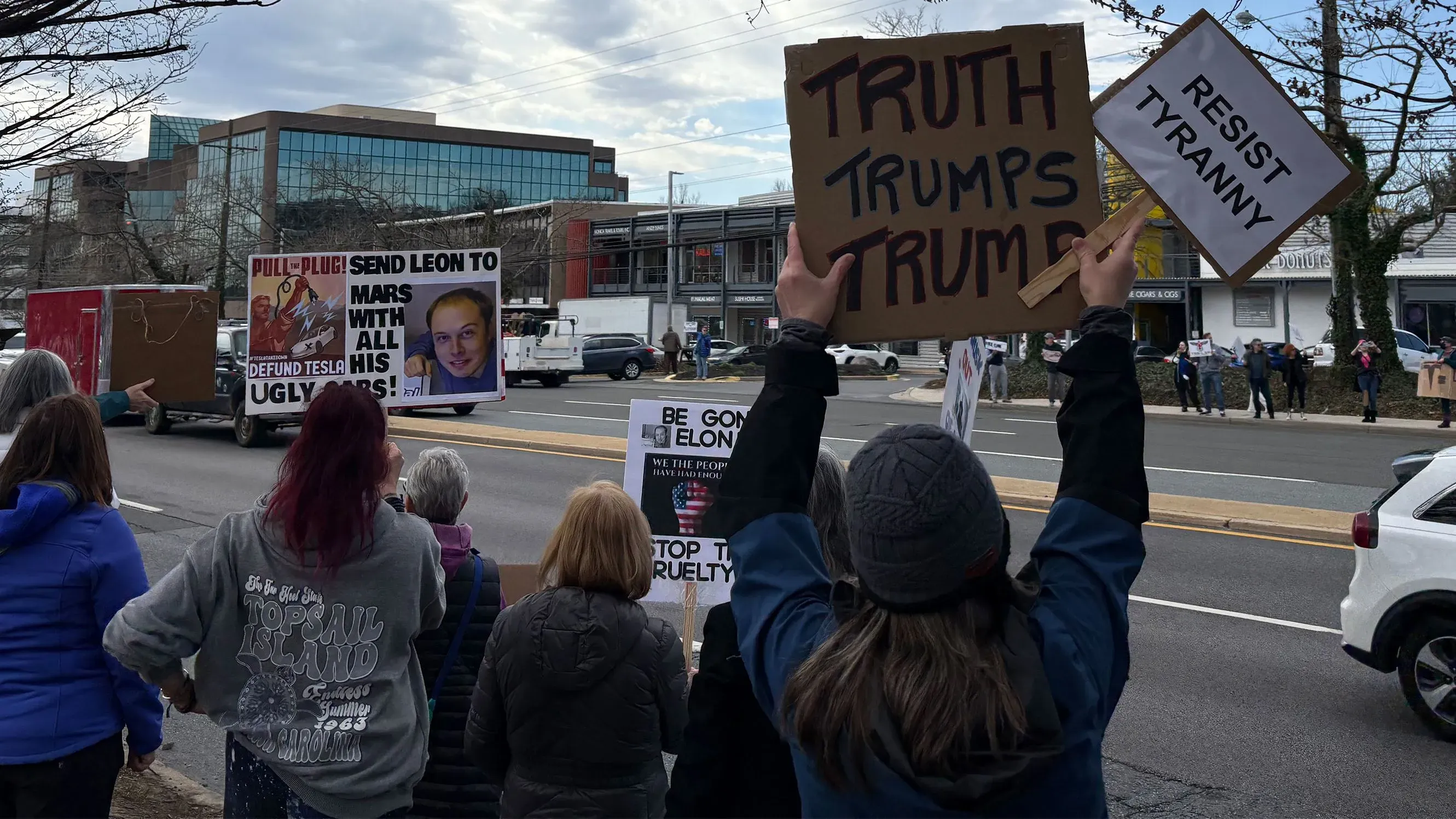 مظاهرة أمام صالة عرض تسلا في روكفيل بولاية ماريلاند، حيث يحمل المتظاهرون لافتات تعبر عن معارضتهم لإيلون ماسك وسياساته.