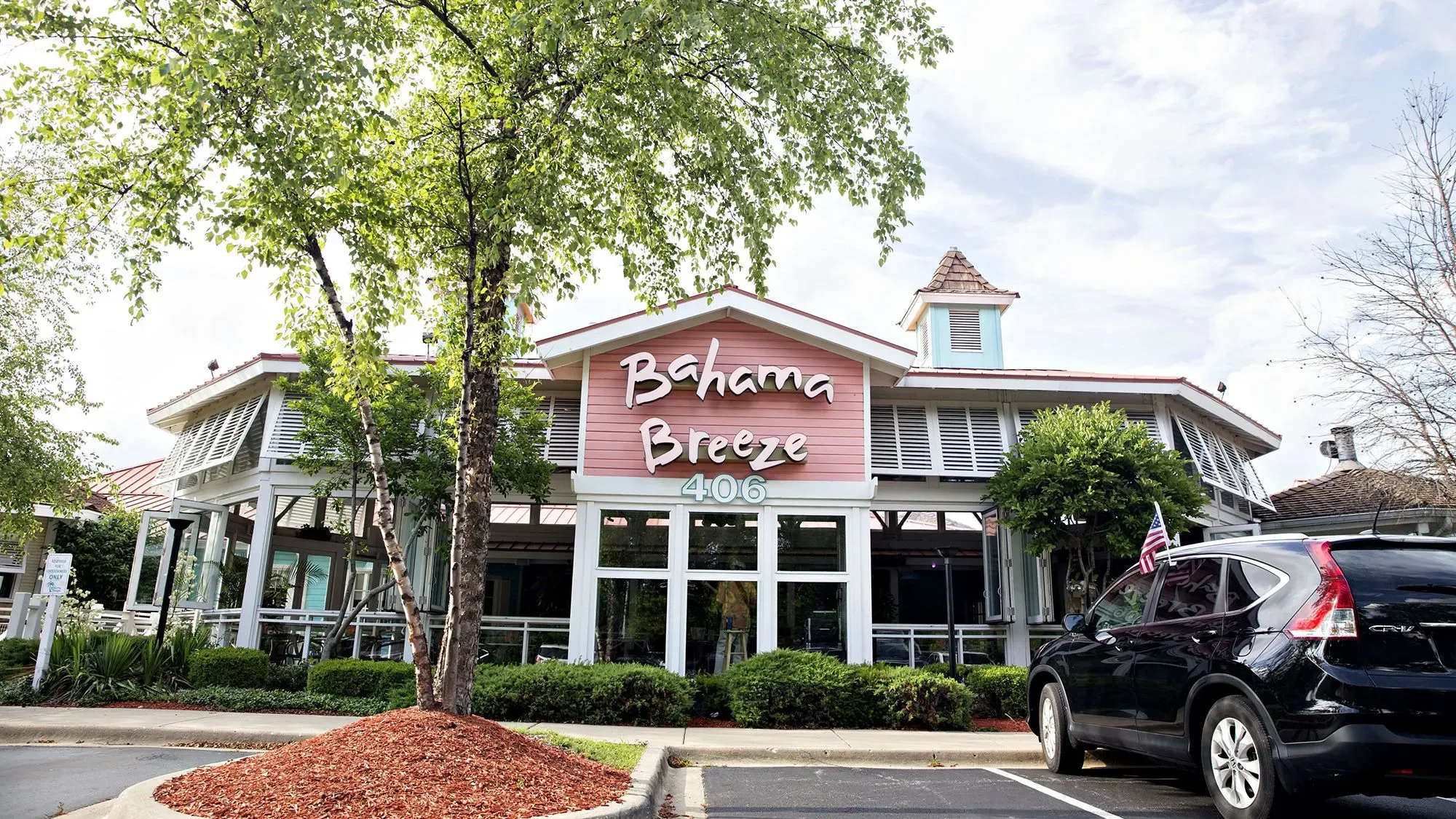 مطعم باهاما بريز، الذي يتميز بتصميمه الكاريبي، يظهر في الصورة مع شجرة أمامية ومركبة متوقفة، في ظل إغلاق 15 موقعًا.