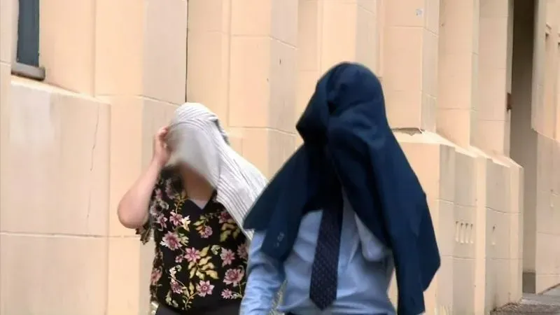 والدا الفتاة يغطيان رأسيهما بملابس أثناء مغادرتهما المحكمة بعد الحكم عليهما بالإهمال، حيث عانت ابنتهما من سوء التغذية.