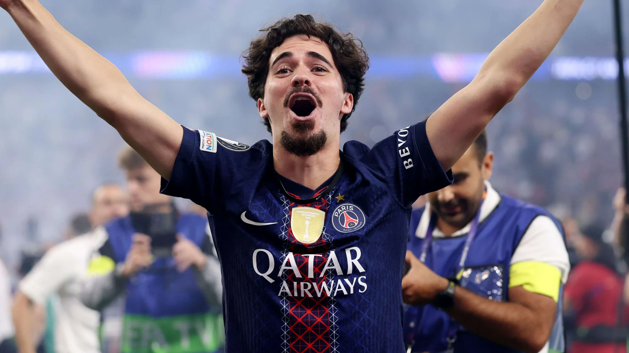 لاعب كرة قدم من باريس سان جيرمان يحتفل بفوز الفريق بدوري أبطال أوروبا موسم 2025-26، مع جمهور في الخلفية.