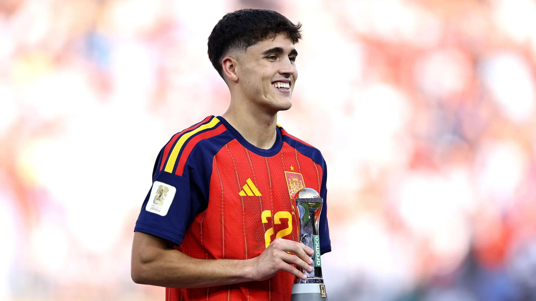 لاعب كرة قدم إسباني شاب مبتسم يحمل جائزة أفضل لاعب شاب في كأس العالم 2026، مرتدياً زي المنتخب الإسباني الأحمر.