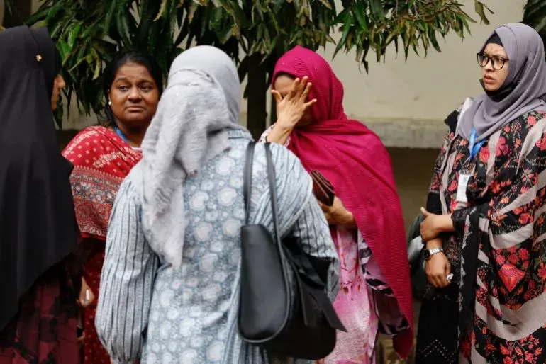 نساء يتجمعن في حالة حزن بعد تحطم طائرة في دكا، حيث قُتل 31 شخصًا، بينهم 25 طالبًا، مما أثار احتجاجات للمطالبة بالعدالة.