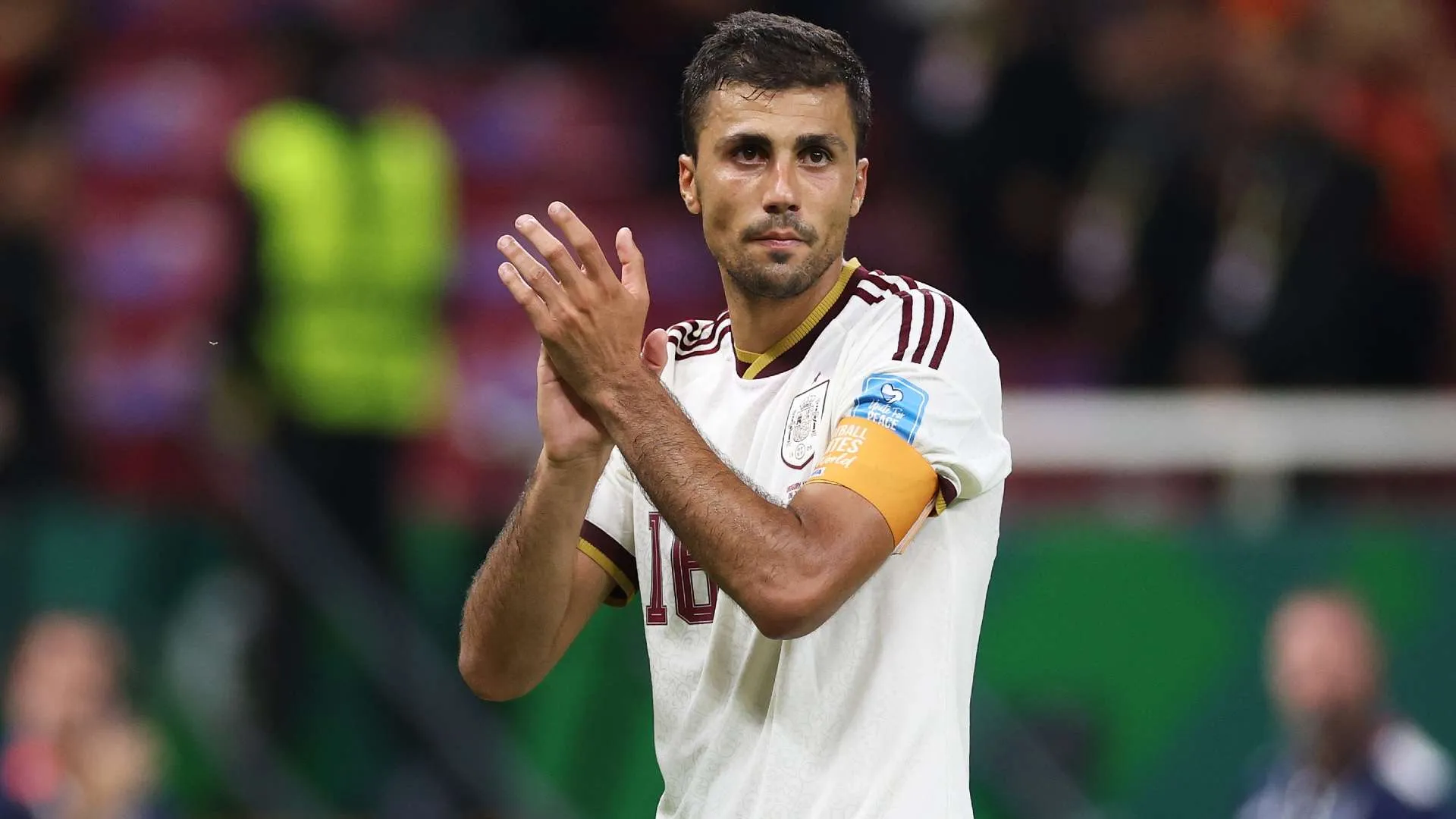 رودري لاعب وسط إسباني يصفق مرتدياً شارة القيادة مع منتخب إسبانيا، في سياق مفاوضات انتقاله بين برشلونة ومانشستر سيتي.