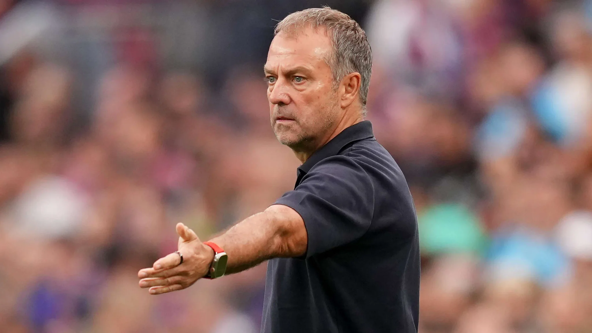هانسي فليك مدرب برشلونة يظهر وهو يوجه تعليمات خلال مباراة، مع خلفية ضبابية للجمهور في ملعب سبوتيفاي كامب نو.