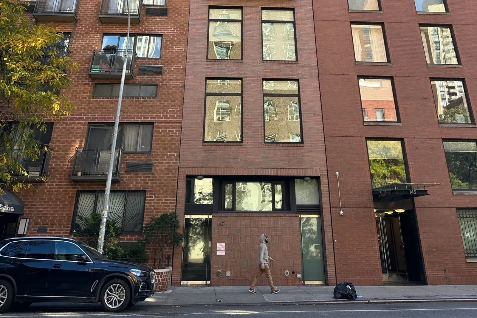 مبنى سكني متواضع في مانهاتن، حيث يُزعم أن ألعاب بوكر غير قانونية كانت تُجرى داخله، يظهر فيه شخص يمشي بجانب سيارة.